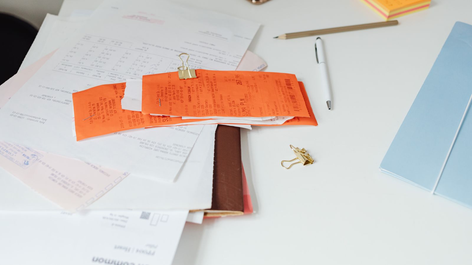 Close-up of a tidy desk with receipts, documents, and office stationery arranged for business organization.