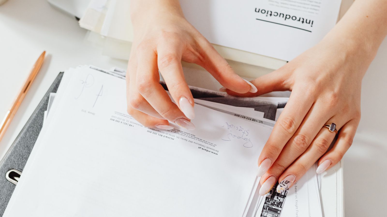Close-up of a woman's hands organizing paperwork on a desk.